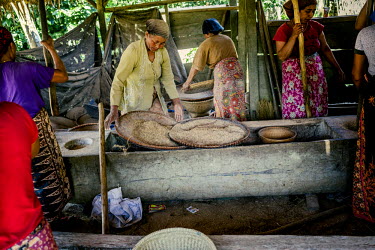 Women dehusking rice by hand. This activity is usually done in groups with long wooden sticks that act as pestles. The same sticks are also used to create percussive music that help the women time the...