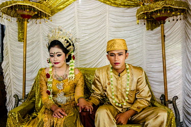 The bride and groom sit together as they are about to start the traditional ceremonies for their wedding.