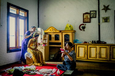 The mother of the village leader, the Aba, lends a hand in making the final finishing touches for the bride to be in preparation for a village wedding.