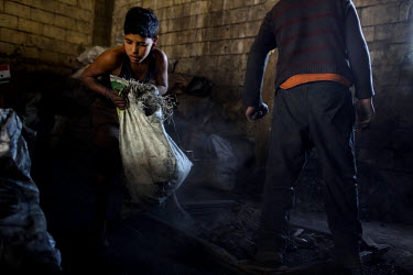 Anas Ezza, 12, empties charcoal onto a sieve at a coal shop in Bebnine. Anas is from Homs (Syria) and came to Lebanon three months earlier with his family, they live in a tented settlement behind the...