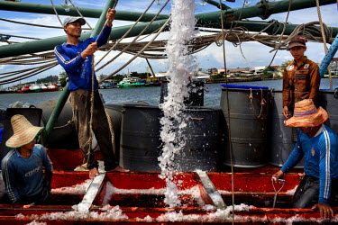 Workers fill a Thai flagged fishing boat's hold with ice at the docks in Songkhla.