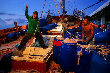 Migrant fisherman unload barrels of fish from a Thai re-supply ship at the docks in Songkhla.