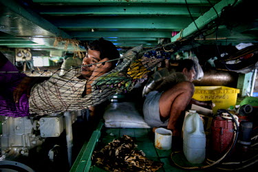 Burmese fisherman serving on a Thai fishing boat rest while moored in Songkhla.