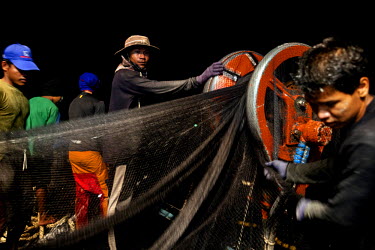 Cambodian migrant fisherman haul in a net on a Thai flagged fishing boat in Thai waters.