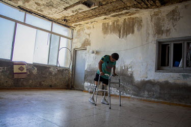 Hussein, 10, practices with his new prosthetic limbs at his family's accommodation in a collective shelter in Tripoli, Lebanon. Hussein was playing with his siblings and cousins in the living room of...