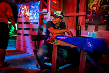 A Thai man drinks beer in a bar in the red light district of Ranong that is frequented by fishermen.