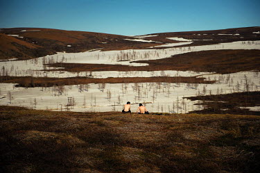 After spending nine months in confined indoor spaces the people of Norilsk like to escape to the tundra when the weather turns nice. Two young man sit on a hillock overlooking a still partially snow c...