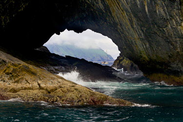A boat seen through a sea arch on the coast of one of the islands of the St Kilda archipelago which lies, isolated, in the Atlantic 40 miles off the western isles of Scotland. It is a dual UNESCO Worl...