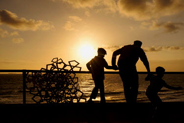 A father and his sons looking at art installations, 'Sculptures by the Sea', on Cottesloe Beach.