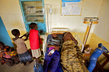 Two patients share the same hospital bed while waiting for treatment in a remote clinic.