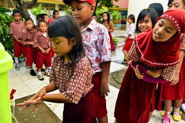 School children line up to wash their hands before class, in a new health/hygiene initiative.