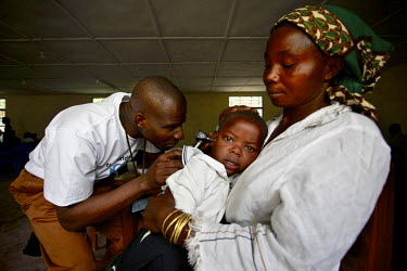 A health worker, specialised in hearing problems, checks the ear of a young child during a camp clinic day.