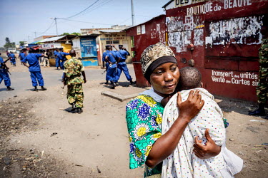A woman carries her child away from police and soldiers who were forcing people off the streets in the Cibitoke district. Residents came out to protest against the proposed third term of President Pie...
