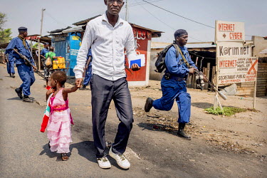 A man walks his child away from police and soldiers who were forcing people off the streets in the Cibitoke district. Residents came out to protest against the proposed third term of President Pierre...