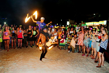 A man and two young boys juggling with fire to entertain the tourists. The inhabitants on the small island have come to depend on the income brought in by the party and it's visitors. The full moon pa...