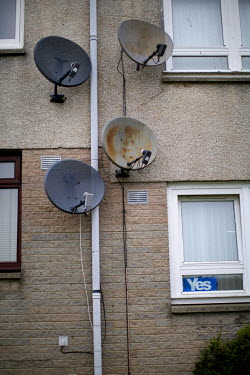 Satellite dishes on the wall of a block of council flats in Aberdeen. Ahead of the Scottish independence referendum in September 2014, a 'Yes' to independence poster has been stuck up in a window of o...