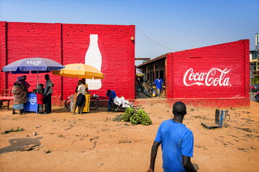 Stall selling mobile phone credits set up infront of building walls covered in a Coca-Cola advertisement.
