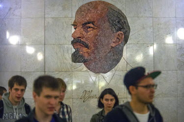 Passengers pass a mosaic mural of Lenin at Biblioteca Im Lenina (The Lenin Library) Metro Station, opened in 1935.