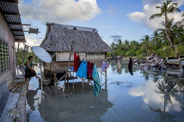 Etana Matthew, 58, jumps from her house to her 'kiakia' a traditional I-Kiribati house, flooded by high tide water. Aberao village, where Etana lives, is threatened by rising seas. The sea wall that s...