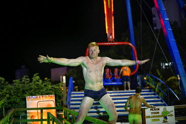 A man, stripped down to his underwear, prepares to take a turn on an amusement ride. Thousands of young tourists visit Magaluf each year seeking cheap alcohol and fun. The new mayor Alfonso Rodriguez,...