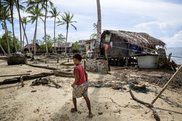 A woman walks through a village on the sea shore on Pamachau Island. Just 40 people live in nine houses on the island.