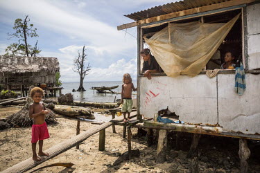 Josephine Kiou (in the middle), a mother of four children, sits at the window of her home with her sister watching their children playing outside. Her house was destroyed by a 'king tide' in 2012 but...