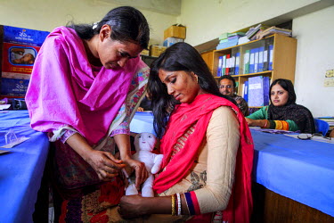 Women practice givng injectable vaccines while taking part in a workshop for health workers.