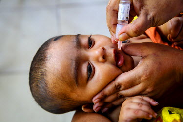 Muna, a Community Health Care Provider, gives an oral vaccine to five month old Shuvo who has been brought by his mother to the vaccination centre as part of the Expanded Program on Immunisation (EPI)...