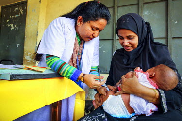 Muna, a Community Health Care Provider, gives an injection to three month old Laboni who has been brought by her mother Sonia to the vaccination centre as part of the Expanded Program on Immunisation...