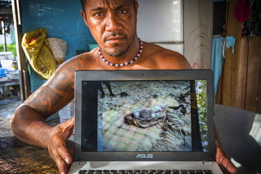 Nelly Seniola, 35, extension officer in the Tuvaluan fisheries department, shows a photograph on his laptop of a corpse that was washed out of a cemetery by a storm surge. Nelly says: 'There were many...