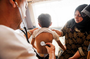 Six year old Mohammed a refugee from Iraq is checked by MSF doctor Dimitris Giannousis at the charity's mobile clinic held in a camper van at Mytiline port.
