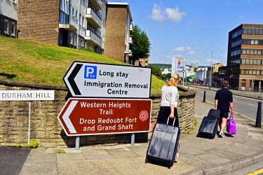 Tourists pull their luggage past a sign in Dover, near the ferry ports, indicating  an 'Immigration Removal Centre'.