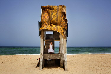 A girl plays in a remnant of a concrete structure bedecked with a large cloth on a beach near the Deir al-Balah refugee camp. She is wearing the party dress she wore the night before at a wedding.