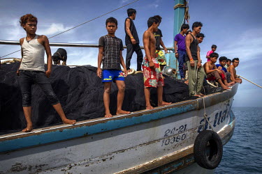 Cambodian migrant fishermen stand on the edge of a Thai flagged fishing boat in Thai waters in The Gulf of Thailand.