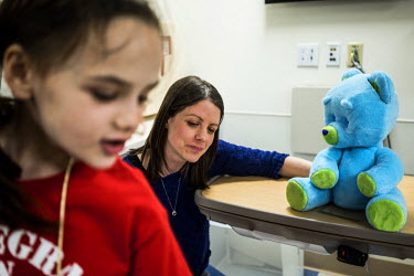 8-year old Beatrice Lipp plays 'I Spy' next to a 'Huggable' with the robotic teddy bear in an hospital room at Boston Children's Hospital while a hospital child-life specialist looks on. Beatrice has...