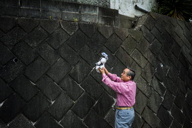 Kouzaburo Sakurai holds an AIBO while his wife Michiko Sakurai (not shown) photographs it near their home in Tokyo.  In 1999, Sony released a series of robotic pets called AIBO or Artificial Intellige...
