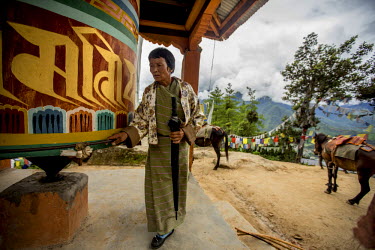 An elderly woman turns a Khor ( prayer wheel ) at Taktsang Monastery during a pilgrimage.