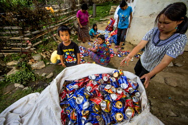 Women and children crush cans for recycling. The cans are sold by the kilo to India where they are recycled. There are no recycling facilities in Bhutan.