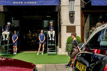 Actors pretending to be umpires and ball girls stand in front of the Ralph Lauren shop on Bond Street. The street, consisting of two sections, has been a fashionable shopping street since the 18th cen...