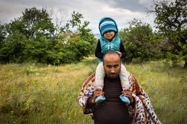 A family of Syrian refugees, from Damascus, walking through fields on the border between Macedonia and Serbia. The family had already tried to cross into Serbia but were pushed back by the authorities...
