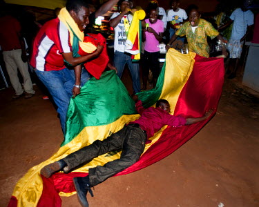 A man rolls in a Ghanaian flag after Ghana defeated the USA in their FIFA World Cup match on 26 June 2010.