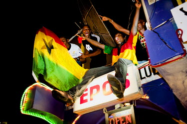 Young men climb on the signage at Epo's, a popular nightspot in Ghana's capital, where they have come to watch a live broadcast of the FIFA World Cup match between Ghana and Germany on 23 June 2010.