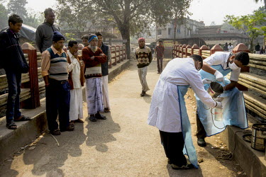 Residents gather to look on as two laboratory assistants, from the Institute of Serology, collect samples from a sewer in Rabindra Nagar in 24 South Pargana, the outskirts of Kolkata, to monitor the p...