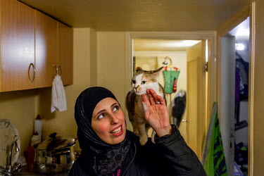 Syrian refugee Heba and her beloved cat Boussy in the kitchen of the small apartment where she lives with her family in Lebanon's Bekaa valley. She smuggled Boussy across the border by putting her in...