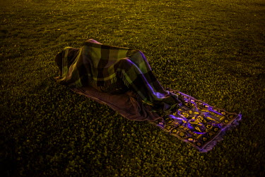 A person sleeps under a blanket in a park in central Vienna. Since the beginning of the migrant crisis in Europe in the summer of 2015 increasing numbers of migrants and refugees are travelling across...