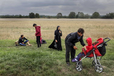 A refugee family from Afghanistan rest by the side of the road leading from the Hungary Austria border to the village of Nickelsdorf where large numbers of migrants and refugees have gathered after tr...