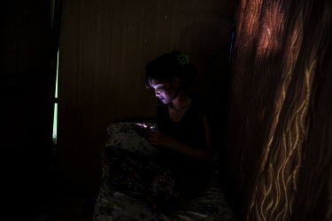 Anaya (23, name changed) checks her mobile phone after completing a massage session for a client. Every day she crosses the border from her hometown of Jaigaon in India to Phuentsholing to work in a m...