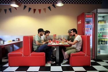 Four Syrian refugees, friends who have travelled together from Turkey, eat a meal at a fast food restaurant in Pancevo outside Belgrade. They have been shopping for clothes at a local branch of H&M in...