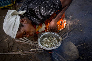 Lucia White, 45, lights a fire to cook dried fish in Khulubvi Camp. The camp was set up following devasting floods in early 2015 that affected half of Malawi and forced around 250,000 people from thei...