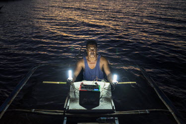 41 year old Roy Ascura holding the lightbulbs he uses for squid jigging on his boat on Polopina island. The island was badly hit by Typhoon Haiyan. Roy says: ‘I learned I would get a boat from Conce...